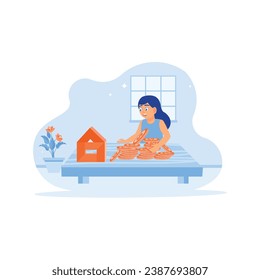 A little girl is sitting on the floor inside a house playing house model and stacks of coins. The little girl's hand protects a pile of cash from falling. House Model Balance Equilibrium concept. 