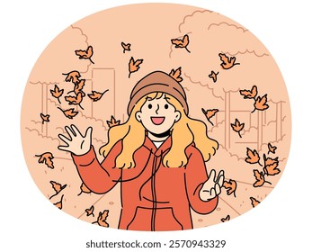 Little girl throws up leaves of autumn trees walking in park and rejoices at end of summer and onset of september. Happy child in autumn jacket and hat laughs standing among falling maple foliage