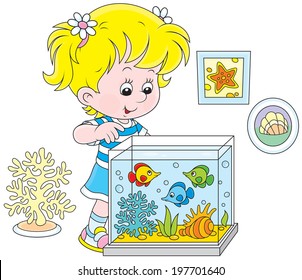 Little girl watching colorful tropical fishes in an aquarium