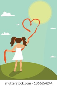 Little girl in a white dress holding a red ribbon heart on on a background of sun and grass