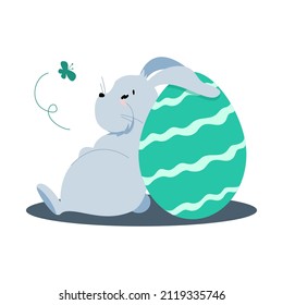 conejito gris de Pascua sentado sobre un huevo de Pascua