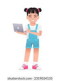 A little happy girl is standing with a laptop in her hands. A beautiful cute white baby in a blue summer jumpsuit. Vector cartoon illustration on a white background.