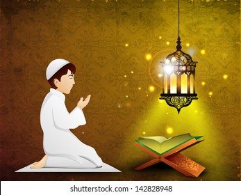 Little Muslim boy in traditional dress praying( reading Namaj, Islamic Prayer) with Islamic religious holy book Quran Shareef in the light of intricate arabic lamp.