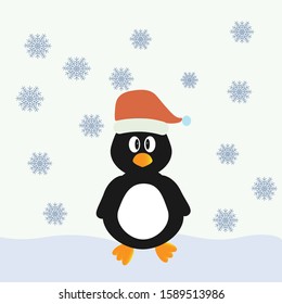 A little penguin in a Christmas hat stands in the snow
