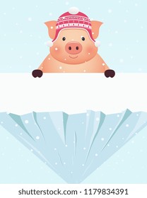 Little pig in hat standing behind snowy rock. Chinese New Year of the Pig.