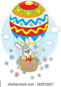 Little rabbit flies in an air balloon colored like an Easter egg and scatters flowers around