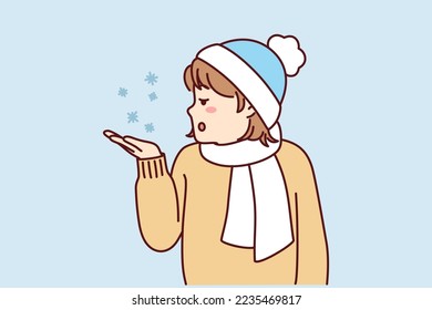 Little teen girl stretches out palm to pick up snowflakes standing outdoors in cold weather. Child in hat and scarf enjoys winter holidays and looks with surprise at falling snow. Flat vector image