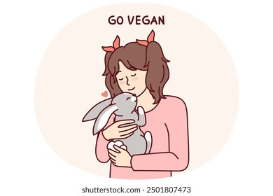 Little vegan older girl hugs rabbit that they wanted to use for food and cook for dinner. Concept of transition to healthy nutrition and promotion of vegan lifestyle from childhood and adolescence