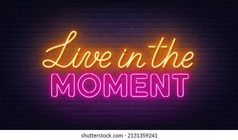Live in the Moment neon lettering on brick wall background.