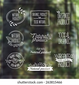 Logotypes set. Badges, labels, ribbons, plants elements, wreaths and laurels, branches. Organic, bio, ecology, eco natural design template. Hand drawing. Vintage vector on blurred background forest