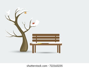 A lonely bench under the snow with leaves and a snow-drenched tree (maple) on a blue background