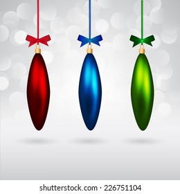 Long multicolor christmas baubles with bows on sparkling background.