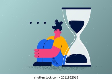 Long wait, delay, appointment concept. Young tired man cartoon character sitting on floor waiting feeling delay exhausted with huge hourglass behind vector illustration