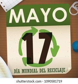 Loose-leaf calendar with recyclable materials around it: notebook paper, cardboard, plastic cap, pull ring can and glass to promote International Recycling Day (written in Spanish).