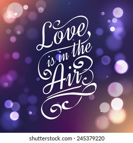 Love is in the air. Calligraphic lettering with bokeh lights.