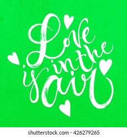 Love is in the air card. Hand drawn lettering. Modern calligraphy. Ink illustration. Design for banner, poster, card, invitation, brochure, t-shirt. Isolated on textured colour abstract background