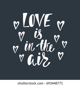 Love is in the air. Romantic handwritten phrase about love with hearts. Hand drawn lettering to Valentines day design, wedding postcards, greeting cards, posters and prints.
