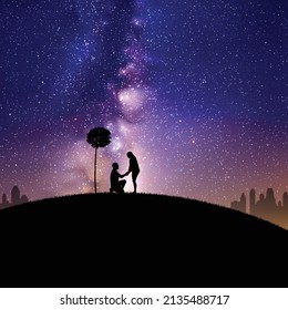 Lovers under tree at park. Marriage proposal. Milky Way at night sky
