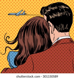 Loving couple looking at a plane taking off in the sky. A man and a woman hug and stand back