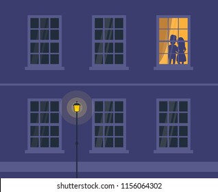 loving couple silhouettes in lighting window house facade at night