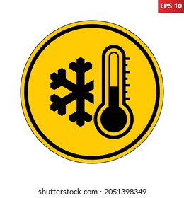 Low temperature warning sign. Vector illustration of yellow circular sign with snowflake and thermometer icon inside. Very cold and freezing. Caution symbol isolated on background. Winter concept.
