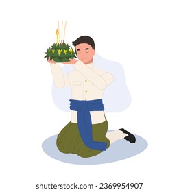 Loy Krathong Traditional Festival. man in Thai traditional dress is sitting and hold krathong up to make a wish before float in river.