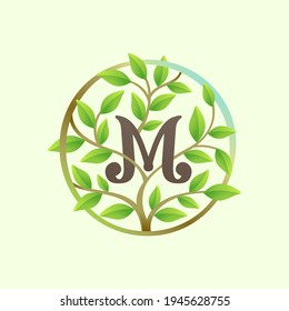 M letter logo made of twisted tree branches and green leaves in circle. Ecology vector font for vegan emblem, botanical identity, creative spring t-shirts, organic merchandise.