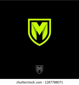 M letter in a shield. M origami monogram consist of green ribbon. Web, UI icon, isolated on a dark background.