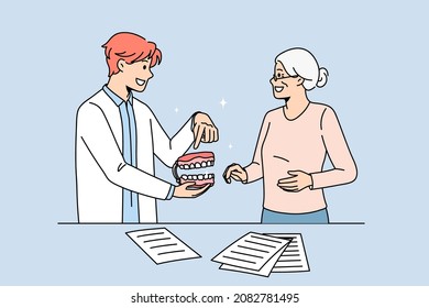 Male Doctor Consult Old Woman Patient About Teeth Prosthesis In Dental Clinic. Man Dentist Show Tooth Model To Senior Female Client. Dentistry And Healthcare. Oral Care. Flat Vector Illustration. 