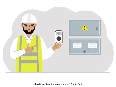 A male electrical engineer holds a digital multimeter in his hand and stands next to an electrical cabinet.