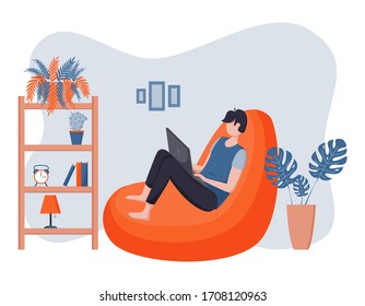 A male freelancer sits in a bean chair and works, study, communicates on social networks in a laptop. The concept of remote work in cozy home environment.Stay home.Flat style.Color vector illustration