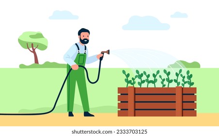 Male gardener waters his plants in bed. Farmer spraying seedlings with hose. Agriculture workers in overalls. Flowers irrigation. Man watering vegetables. Gardening work