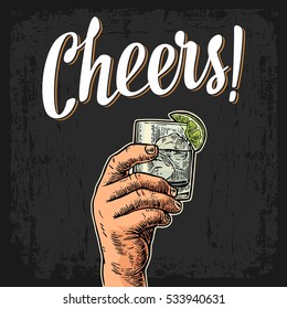 Male hand holding a glass with gin, lemon and ice cubes. Cheers toast lettering. Vintage vector color engraving illustration for label, poster, invitation to a party. Isolated on dark background.