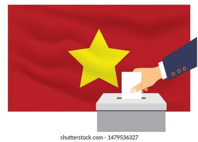 Male hand puts down a white sheet of paper with a mark as a symbol of a ballot paper against the background of the Vietnam flag. Vietnam the symbol of elections.