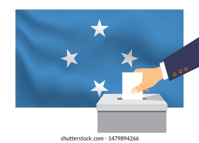 Male hand puts down a white sheet of paper with a mark as a symbol of a ballot paper against the background of the Micronesia flag. Micronesia the symbol of elections.

