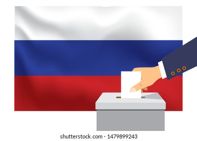 Male hand puts down a white sheet of paper with a mark as a symbol of a ballot paper against the background of the Russia flag. Russia the symbol of elections.
