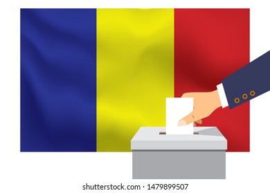 Male hand puts down a white sheet of paper with a mark as a symbol of a ballot paper against the background of the Romania flag. Romania the symbol of elections.
