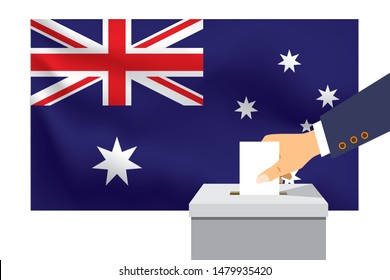 Male hand puts down a white sheet of paper with a mark as a symbol of a ballot paper against the background of the Australia flag. Australia the symbol of elections.