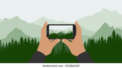 Manos masculinas sostienen el teléfono y toman fotos de la hermosa naturaleza, paisaje. Silhouette de bosque verde sobre el fondo de las montañas. Ilustración del vector