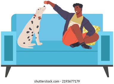 Male Pet Owner With Dog Training, Playing, Sitting On Couch At Home Isolated Concept. Man Feeding Puppy, Domestic Animal, Human Companion While Training. Pet Follows Command Of Person With Dog Food