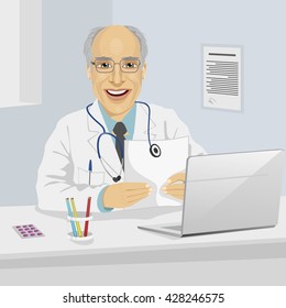 Male senior doctor holding medical prescription sitting in office with laptop