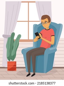 Male sitting on couch at home, chatting, communicating using tablet electronic device. Man talking by phone on sofa. Male sits with smartphone. Distance learning, freelance and internet entertainment