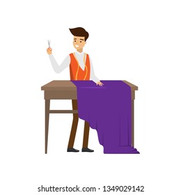 Male tailor standing at table with scissors in hand ready cut purple cloth