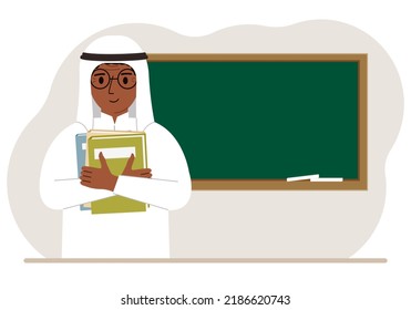 Male teacher with books on the background of the school board.