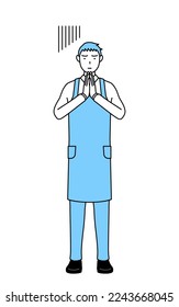 A man in an apron apologizing with his hands in front of his body.