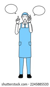 A man in an apron pointing while on the phone.