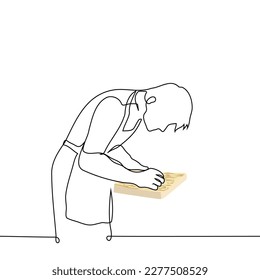  el hombre en un delantal está procesando un trozo de madera - un vector de dibujo de una línea. el concepto de artesano se dedica a la transformación de productos de madera