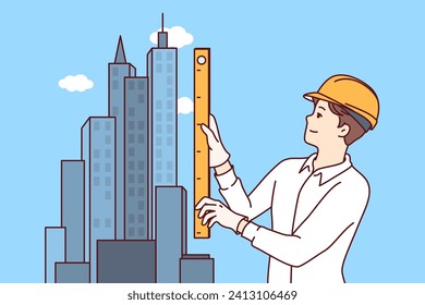 Man architect designs construction of skyscraper and stands near models of downtown holding ruler in hands. Guy works as engineer in construction business, creating architectural plan for new project