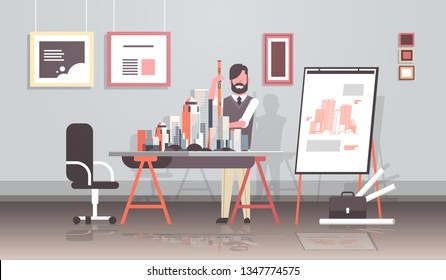 man architect holding level engineer working with new building city model for urban panning project concept house blueprint modern office studio interior horizontal full length