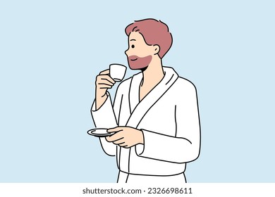 Man in bathrobe drinks coffee enjoying hot tart drink after waking up in morning. Successful young man with tea having rest in hotel or using services of spa center during vacation or weekend